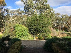 A pathway leading through a garden with various trees and shrubs.