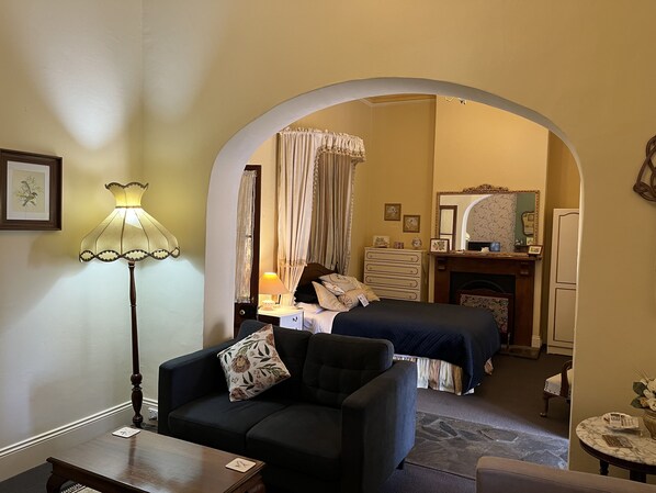 A hotel room with a bed, a sofa, a lamp, a dresser, and a mirror.