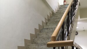 Un escalier avec une main courante en bois et des balustres en métal noir, menant à l’étage supérieur.
