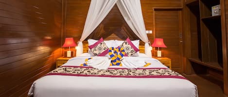 A wooden room with a bed, two bedside lamps, and a canopy bed.