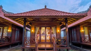 A traditional wooden building with a tiled roof and a central entrance with steps. - The Bridge Huts (Ceningan Island)