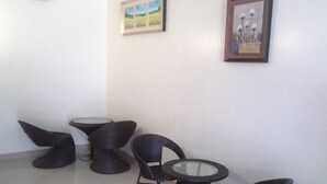 A corner of a room with a round table and four chairs, two of which are angled. There are two framed pictures on the wall. - Meaco Hotel - Calbayog (Calbayog)