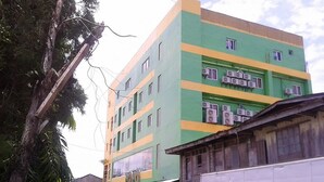 A multi-story building with a green and yellow facade, air conditioning units, and a visible storefront. - Meaco Hotel - Calbayog (Calbayog)