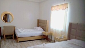 A hotel room with two beds, a desk, a chair, a round mirror, and a window with curtains. - Meaco Hotel - Calbayog (Calbayog)
