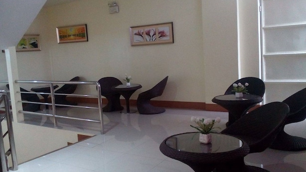 A reception area with a staircase, modern chairs, and tables, featuring artwork on the walls. - Meaco Hotel - Dipolog (Dipolog)