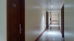 A long, narrow hotel corridor with doors on both sides, a tiled floor, and a ceiling with recessed lighting. - Meaco Hotel - Dipolog (Dipolog)