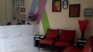 A reception area with a marble counter, red chairs, and framed certificates on the wall. - Meaco Hotel - Dipolog (Dipolog)