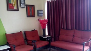 A living room with two red sofas, a small table, a vase with red flowers, and a clock on the wall. - Meaco Hotel - Dipolog (Dipolog)