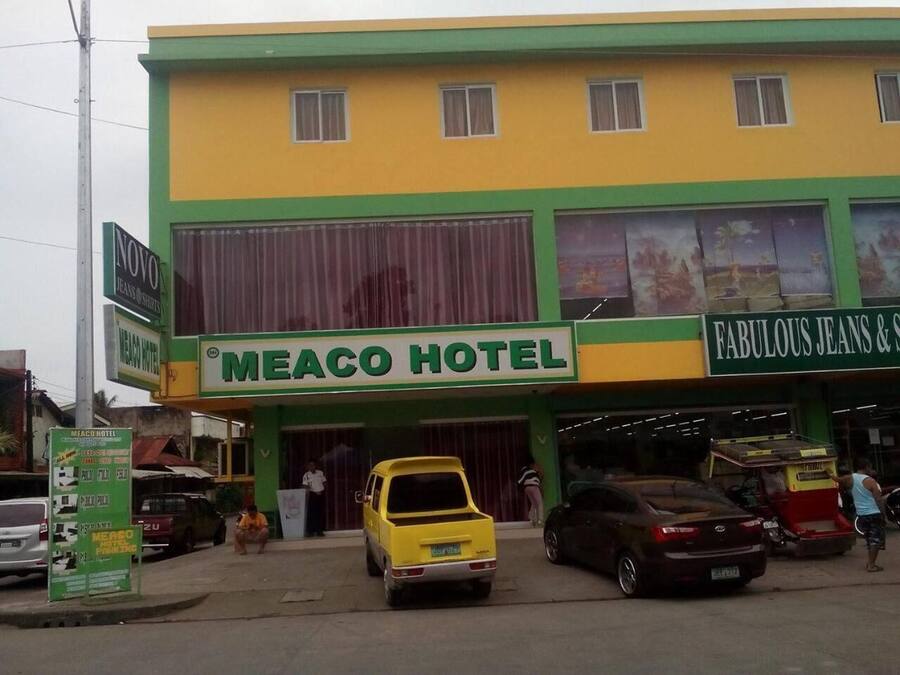 A hotel with a green and yellow facade, a sign for 'Meaco Hotel', and a storefront for 'Fabulous Jeans & Shoes'.