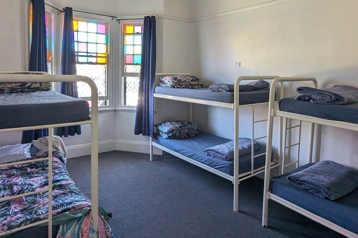 Un dormitorio con literas, ventilador de techo y ventana con cortinas coloridas.