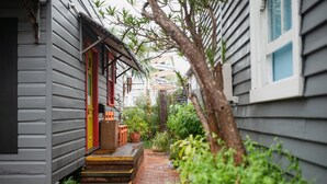 A narrow brick pathway leading to a house with a red door and a small porch area. - Backpackers Newcastle (Hamilton East)