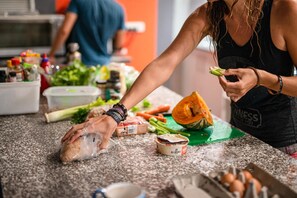 A person preparing food on a kitchen counter with various vegetables and packaged items. - Backpackers Newcastle (Hamilton East)