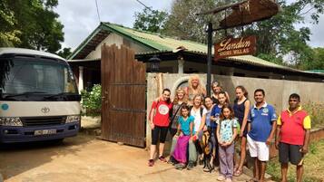 A group of people standing in front of a building with a sign that reads "Landrum Sigiri Village."