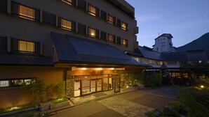A hotel with a traditional Japanese architectural style, featuring a stone entrance, wooden gates, and a tiled roof.