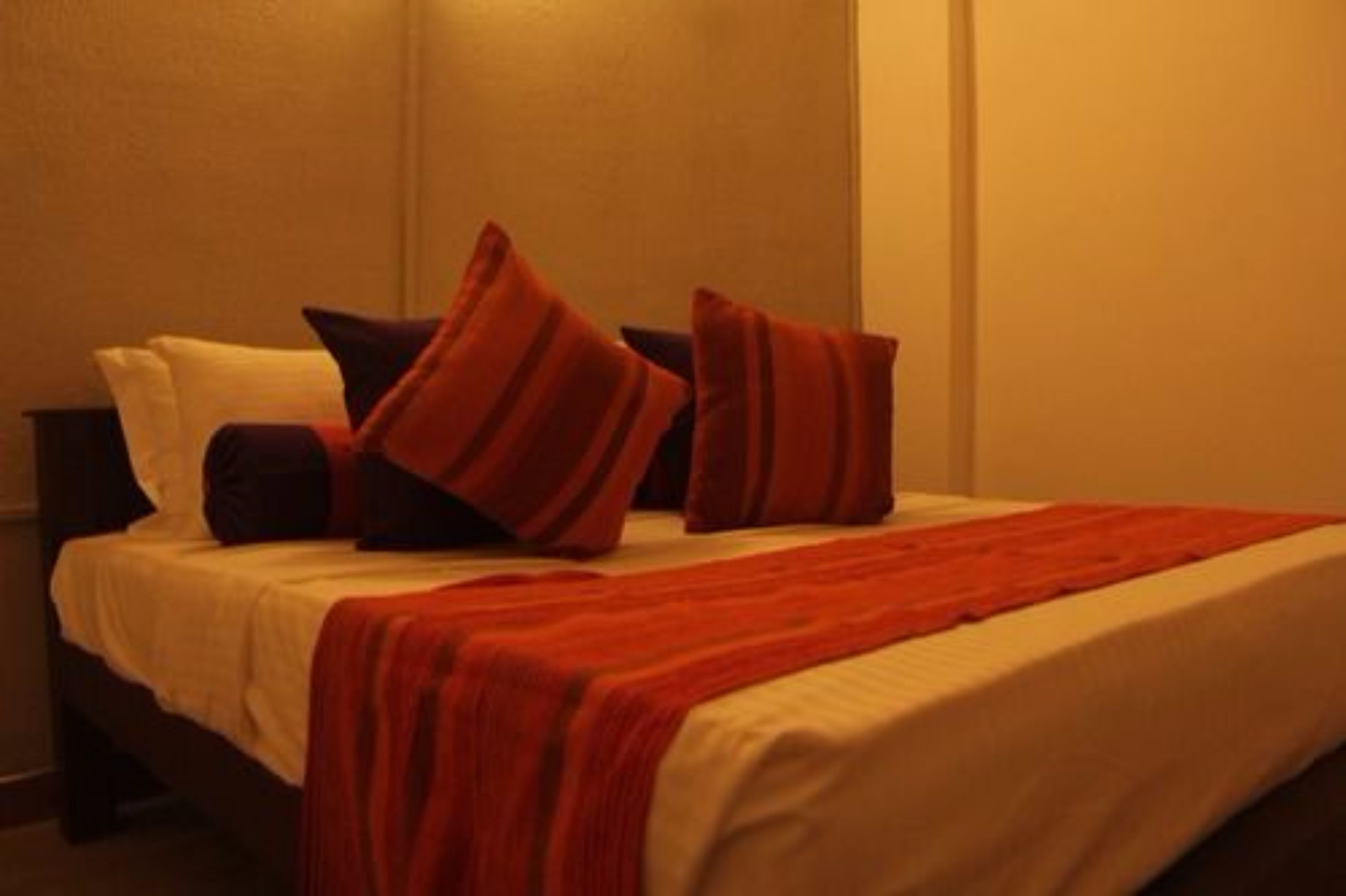 A bed with a white and red bedspread, multiple pillows, and a red blanket.