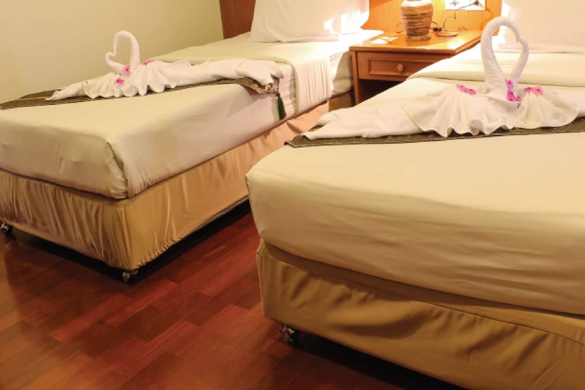 Two single beds with white linens and decorative swan-shaped towels.