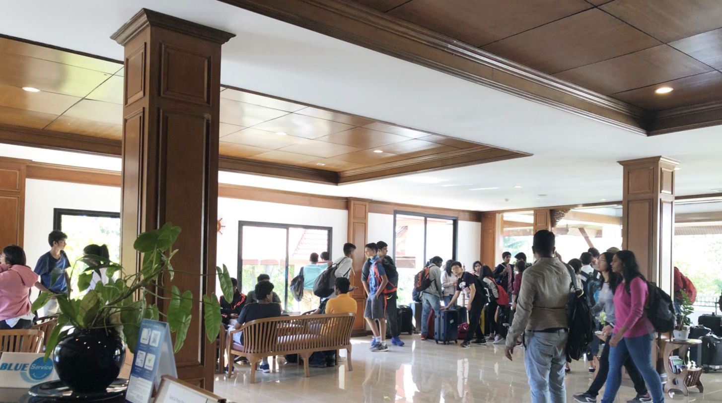 A spacious lobby with wooden columns, a reception desk, and a seating area.