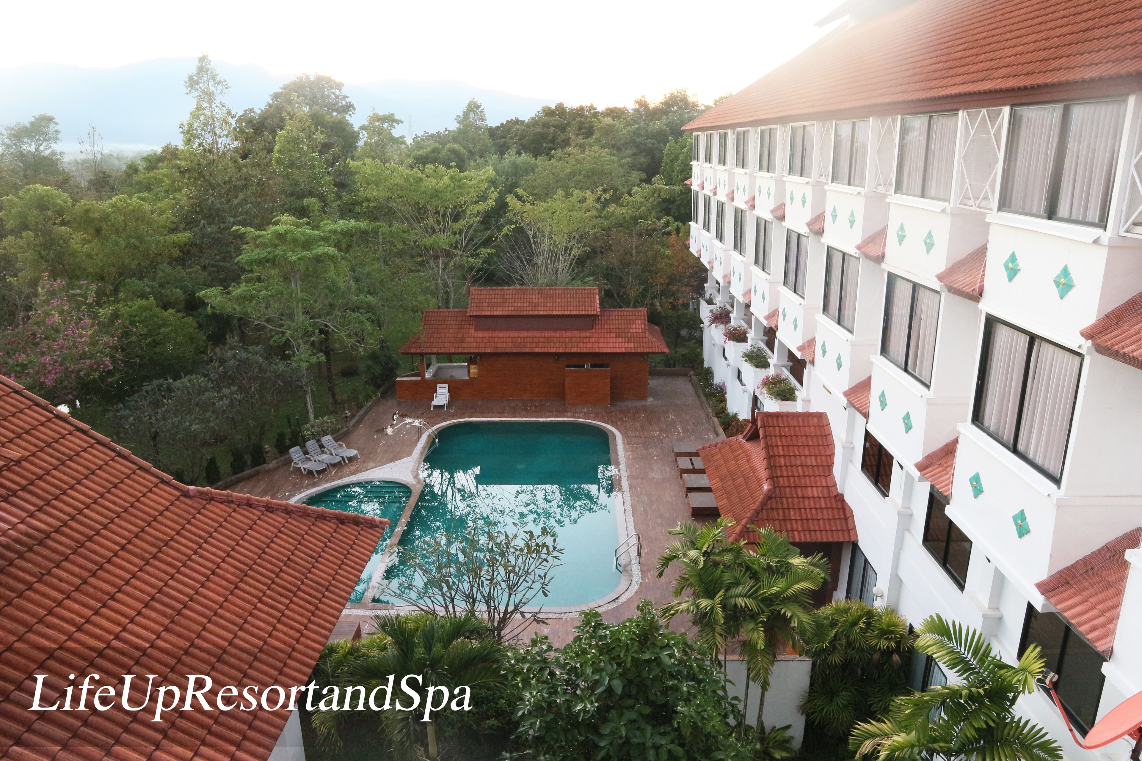 A resort with multiple swimming pools, a building with balconies, and lush greenery in the background.