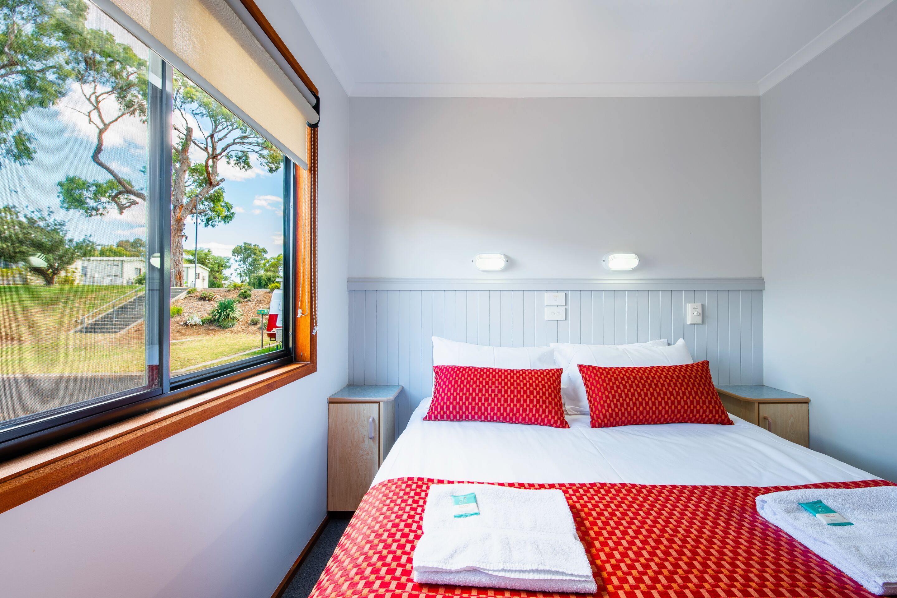 Ett hotellrum med en säng, två sängbord, ett fönster med utsikt över omgivningen och ett vitt tak.