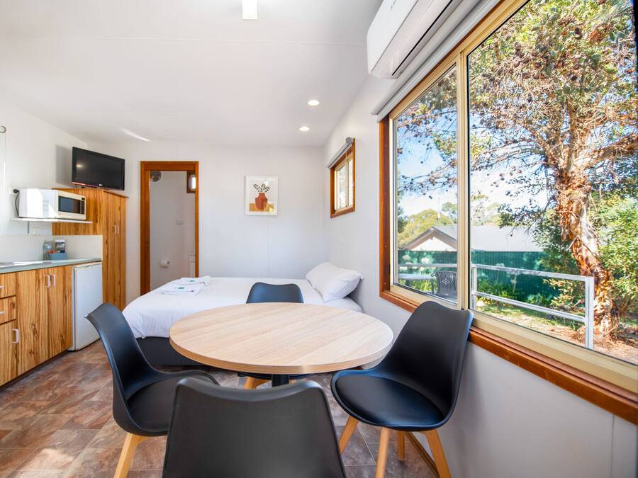 Una cocina moderna con armarios de madera, un microondas y un comedor con mesa redonda y cuatro sillas.