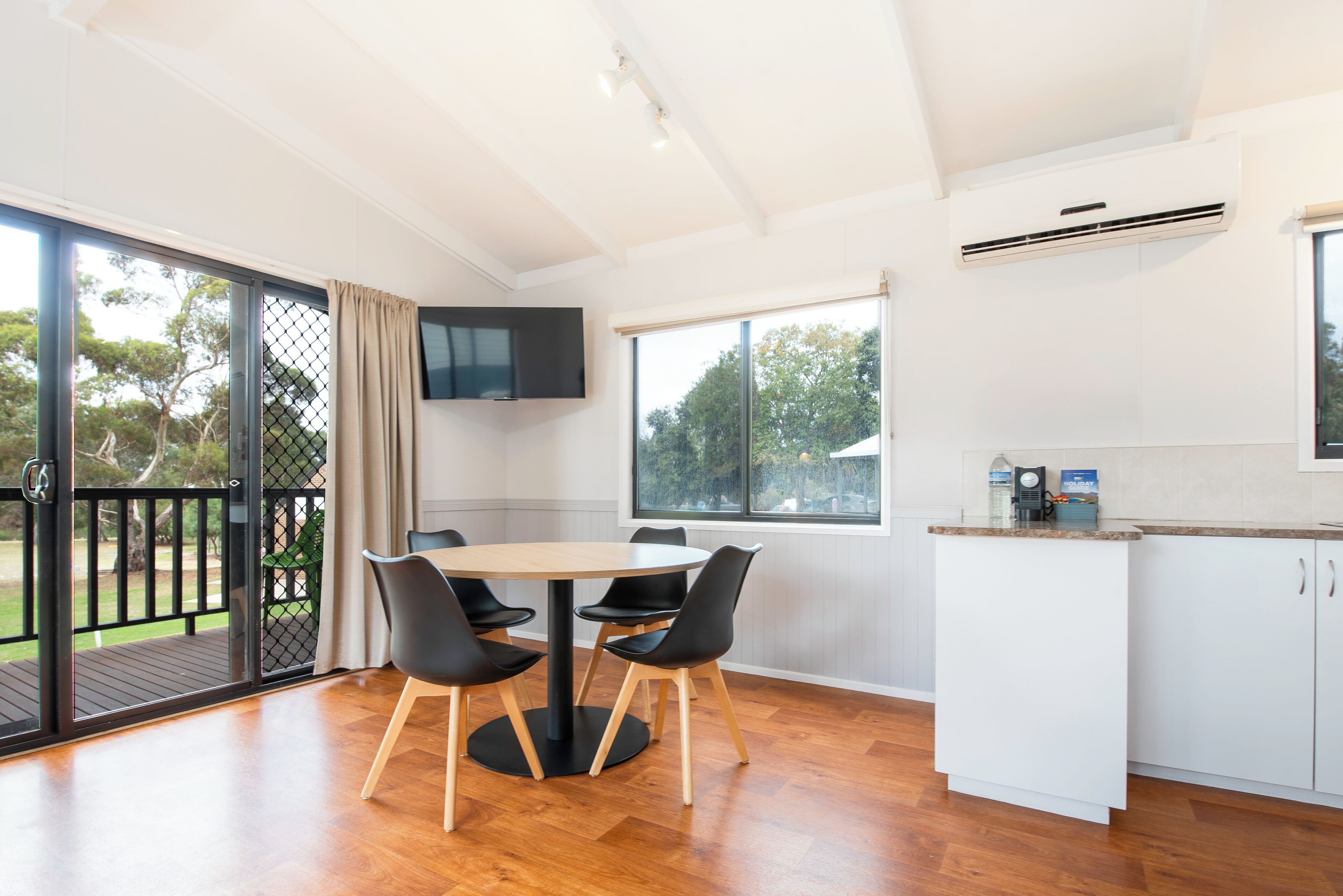 Una cocina moderna con comedor, televisor montado en la pared y vistas al exterior.