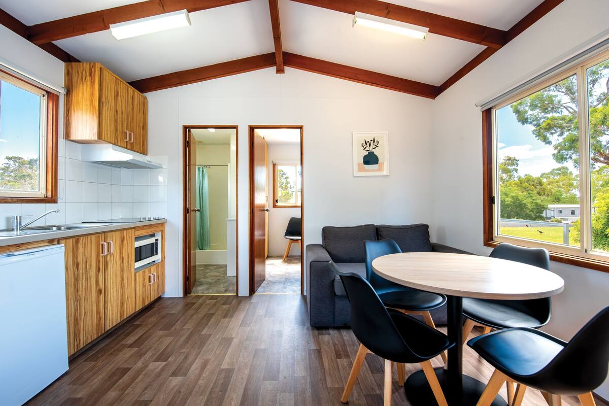 A modern kitchen with wooden cabinets and a dining area with a round table and chairs.