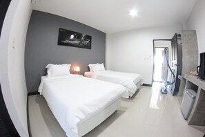 A hotel room with two beds, a small desk, a TV, and a door leading to a bathroom. - Plus Hotel Loei (Wang Saphung)