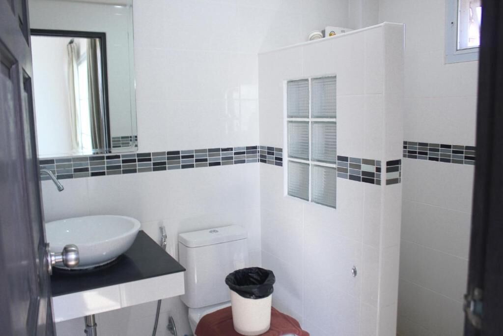 Un baño con un lavamanos blanco, un inodoro y un cubo de basura.