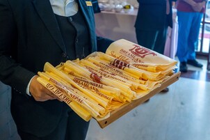 Una persona sosteniendo una bandeja con servilletas dobladas con la etiqueta "Dreamland" y "GOLD RESORT & HOTEL".