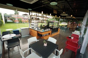 Una cafetería con mostrador, zona de estar y vistas al exterior.