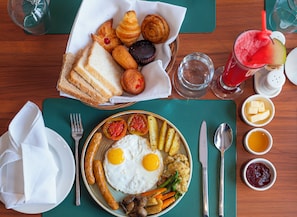 A breakfast setting with eggs, sausages, vegetables, toast, pastries, and a drink. - Dreamland Gold Resort (Tilottama)