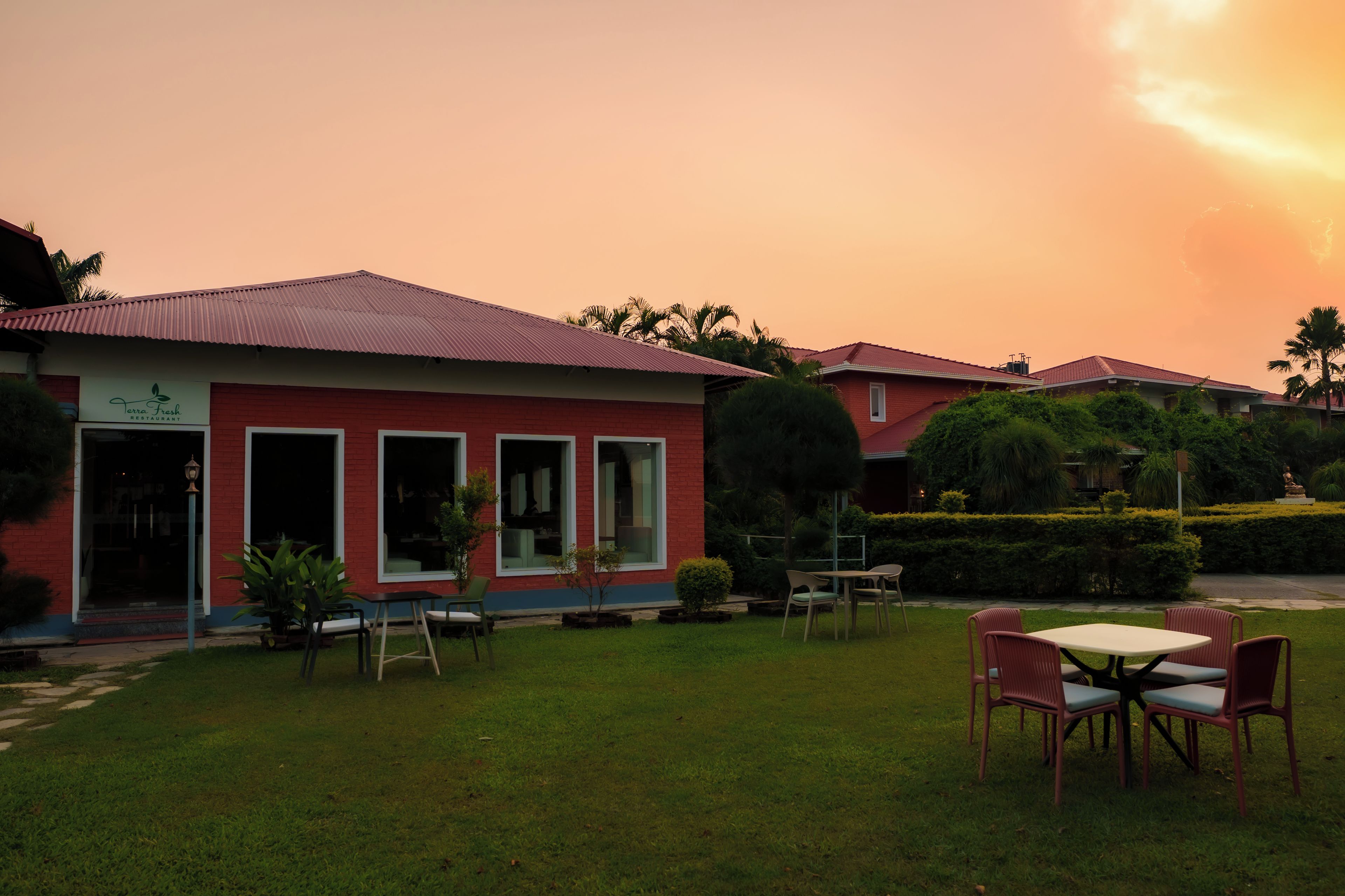 Un bâtiment rouge avec une enseigne indiquant « Terra Fresh Restaurant », et une pelouse bien entretenue avec des tables pour les clients.