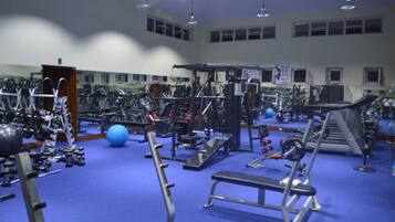 Un gimnasio con diversos equipos de ejercicio, como cintas de correr, máquinas de pesas y pesas libres.