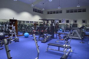 Un gimnasio con diversos equipos de ejercicio, como cintas de correr, máquinas de pesas y pesas libres.