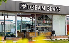 A coffee shop named 'Dream Beans' with a visible counter, seating area, and a view of the surrounding area. - Dreamland Gold Resort (Tilottama)