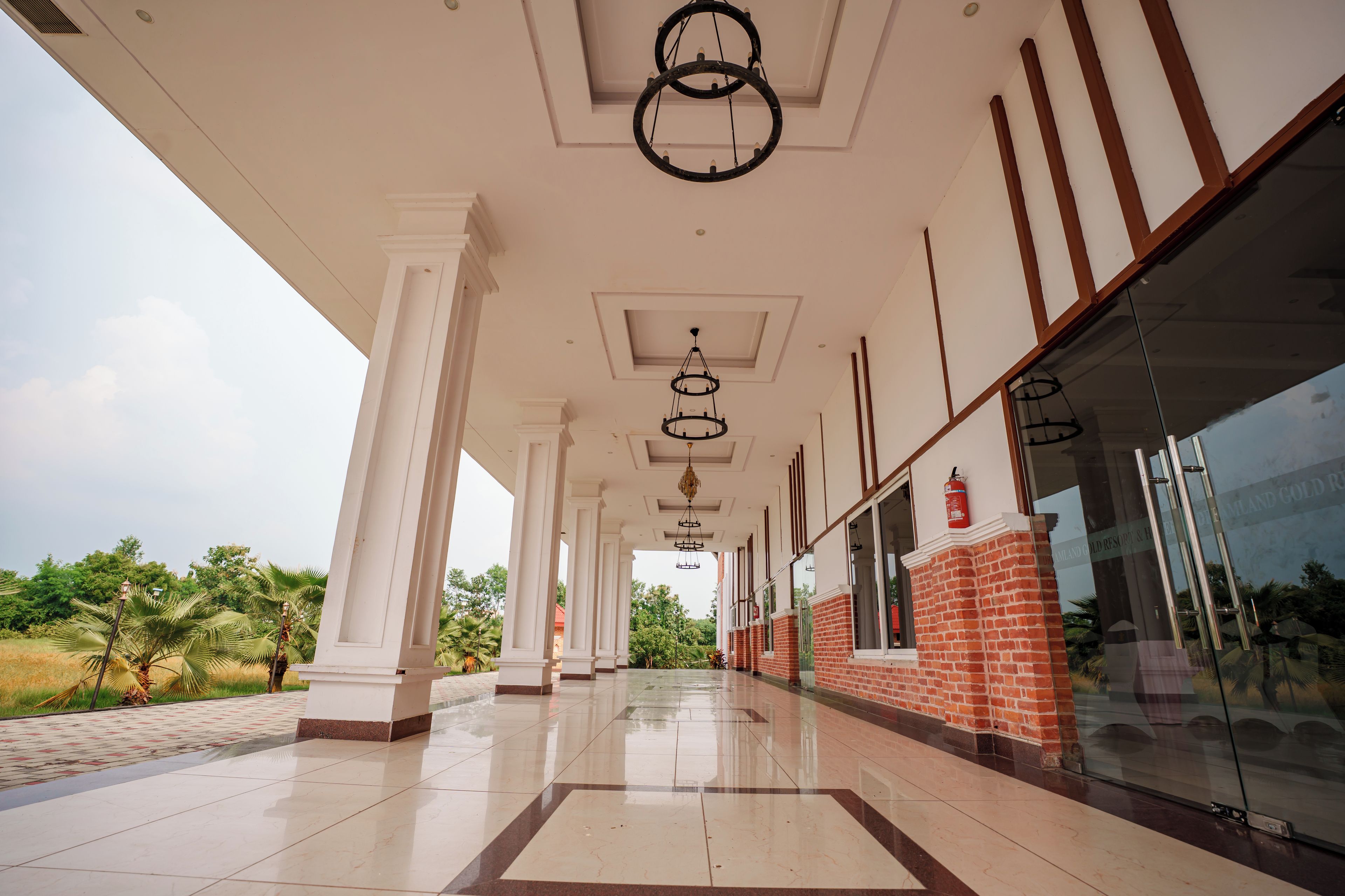 A covered walkway with columns, a glass entrance, and a fire extinguisher.