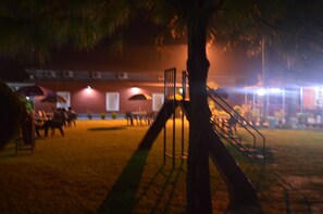 Espacio al aire libre de noche con una escalera, un edificio de ladrillo y un grupo de personas.