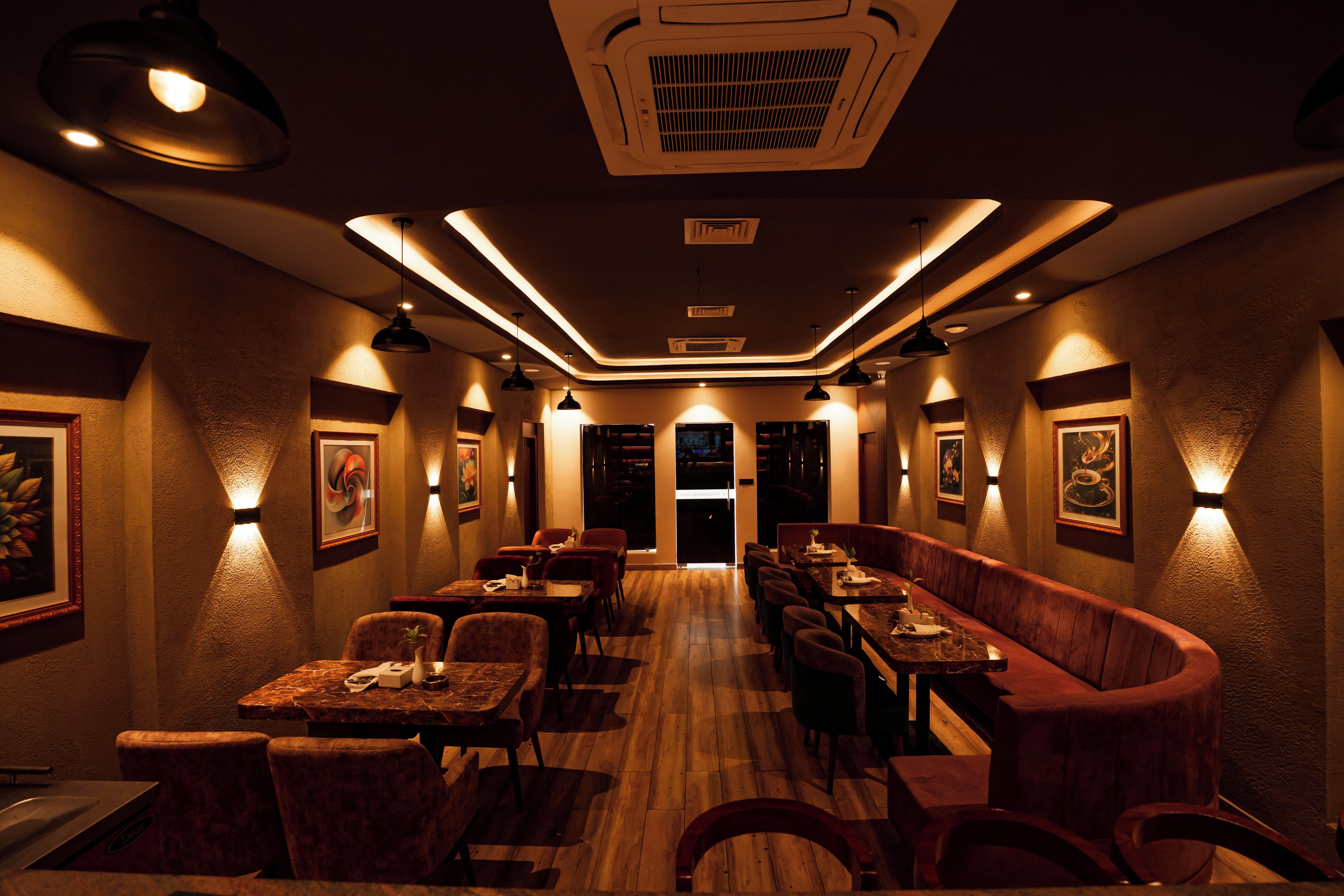 A restaurant with a long counter, booths, and a variety of seating options.