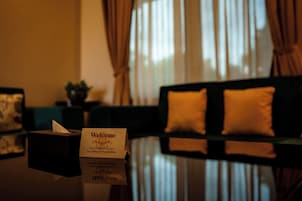 Habitación de hotel con mostrador de recepción, un cartel que dice 'Bienvenido' y un reflejo en la mesa de vidrio.
