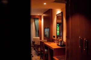 Habitación de hotel con un escritorio de madera, una silla, un televisor y una ventana con cortinas.