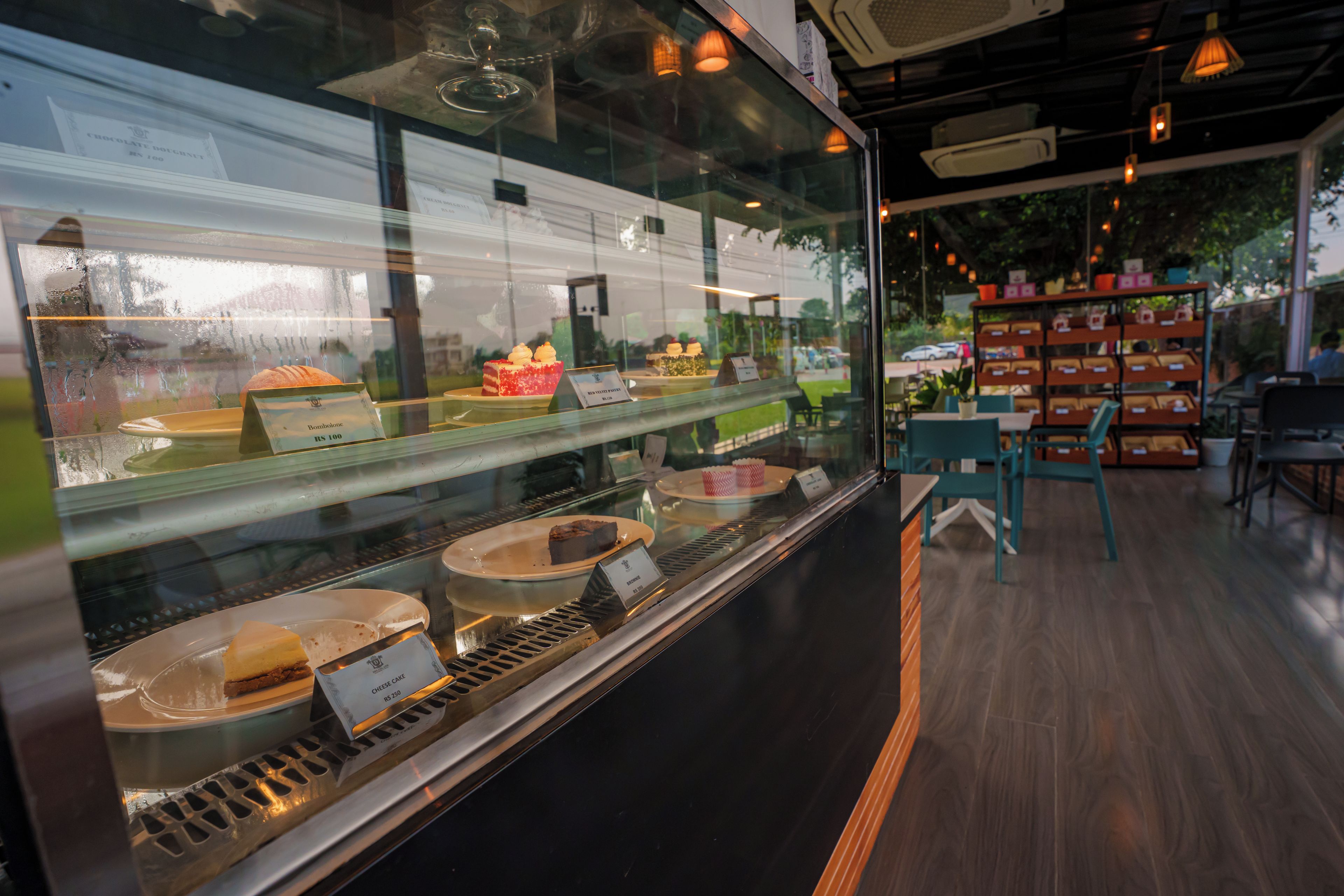A bakery display case with various baked goods and a seating area with tables and chairs.