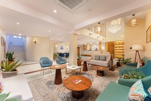 A spacious lobby with a staircase, seating area with sofas and chairs, and a reception desk. - Dreamland Gold Resort (Tilottama)