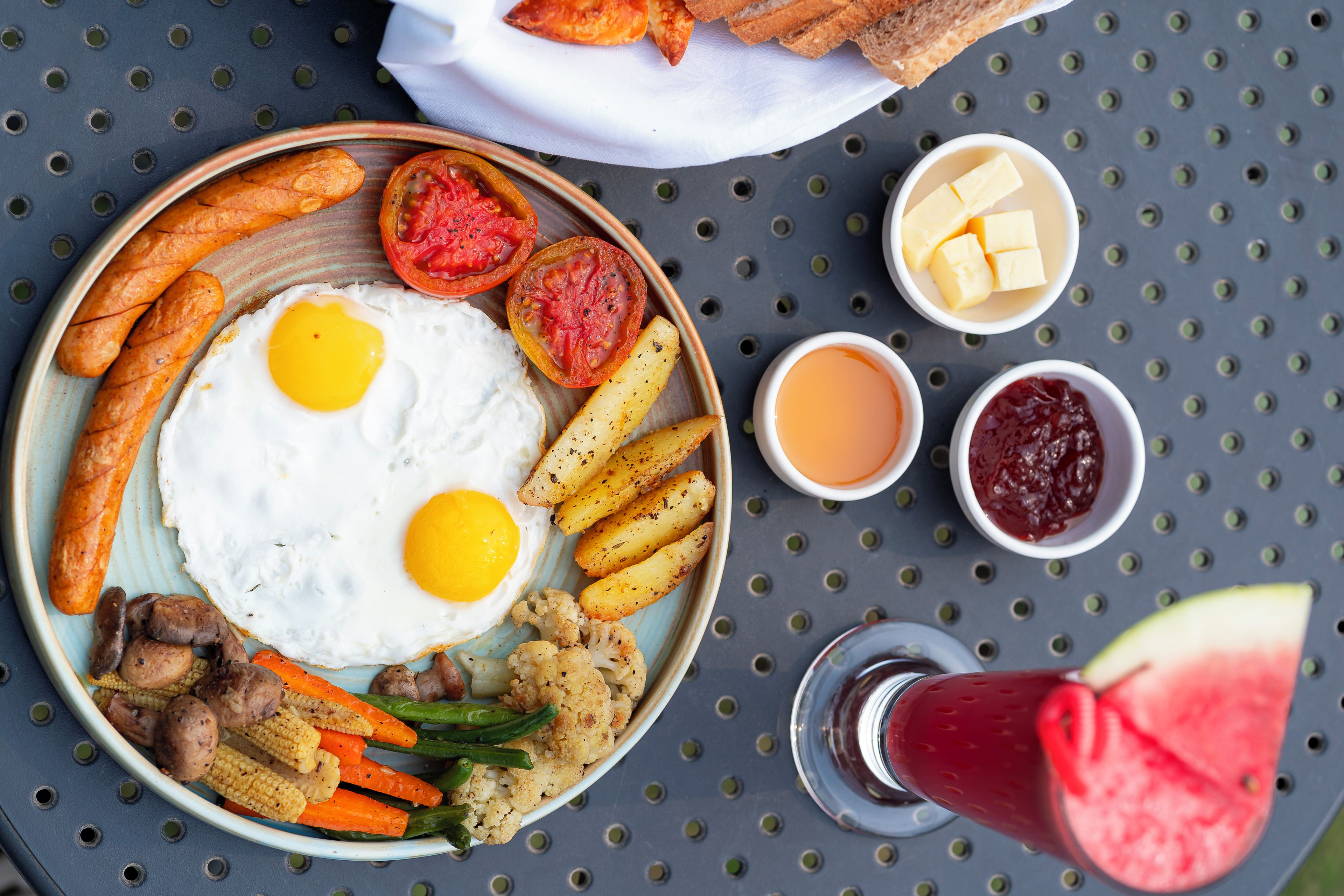 A plate of breakfast food including eggs, sausages, potatoes, and vegetables.