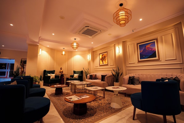 Un hall de hotel bien iluminado con diversas opciones de asientos, incluyendo sofás y sillones, dispuestos alrededor de una mesa de centro.