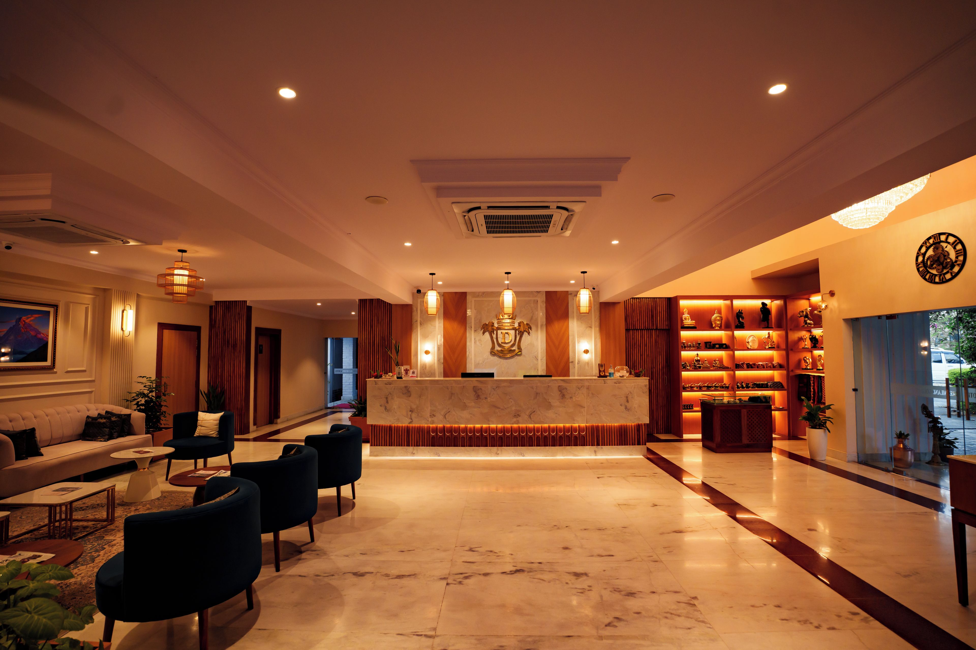 Vestíbulo de hotel con recepción, zona de estar y exhibición de objetos decorativos.