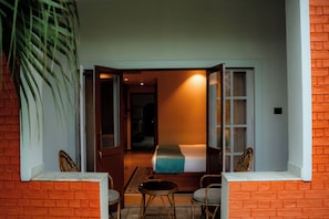 Una habitación con una cama, dos sillas, una mesita y una planta.
