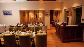 A restaurant with a long counter, multiple dining tables, and chairs.