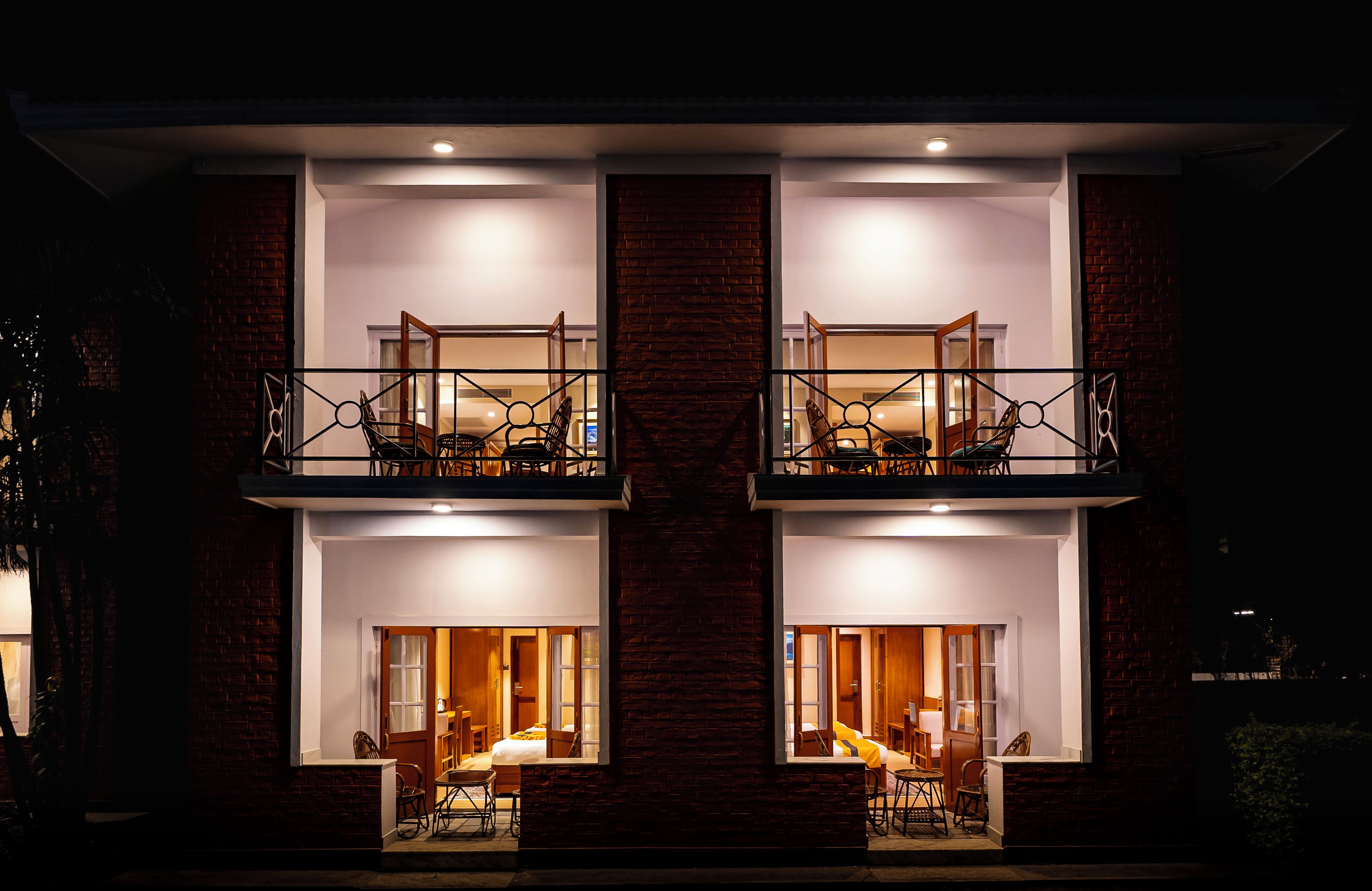 Un edificio de dos pisos con balcones, un comedor y un dormitorio visibles a través de las ventanas.
