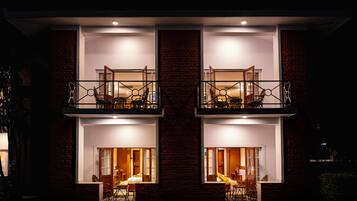 Un edificio de dos pisos con balcones, un comedor y un dormitorio visibles a través de las ventanas.