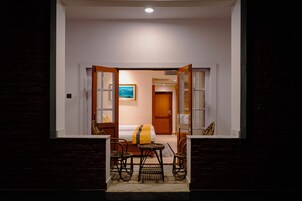 Una habitación de hotel con una cama, una mesita pequeña, dos sillas, un tapete y un cuadro en la pared.